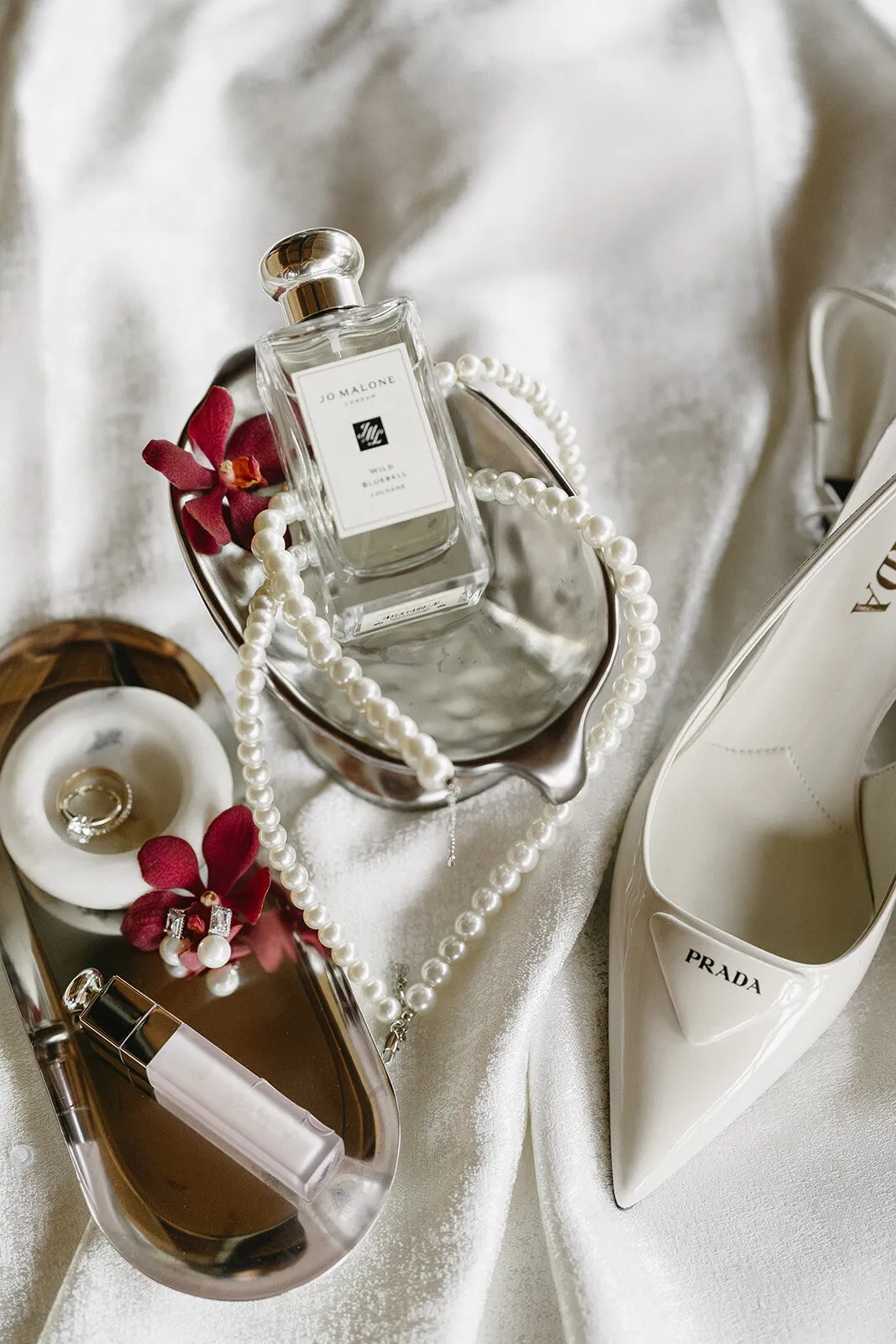 Getting-ready flat lay of heels, perfume, and pearls