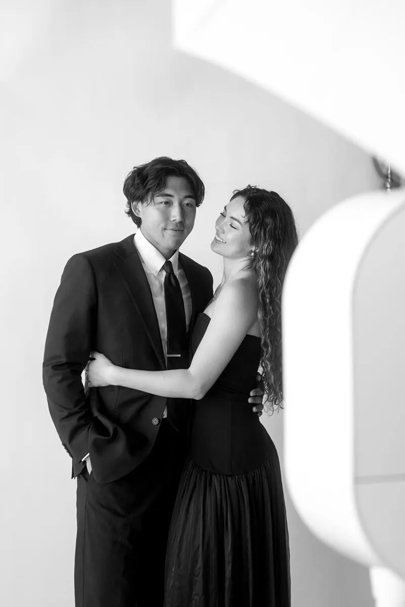 Couple posing together in formal attire in front of a photobooth camera setup.