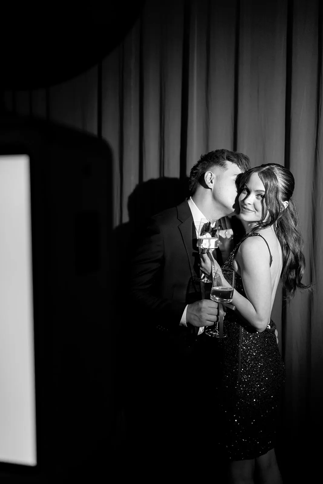 Couple toasting beside the photo booth at a Lorem celebration